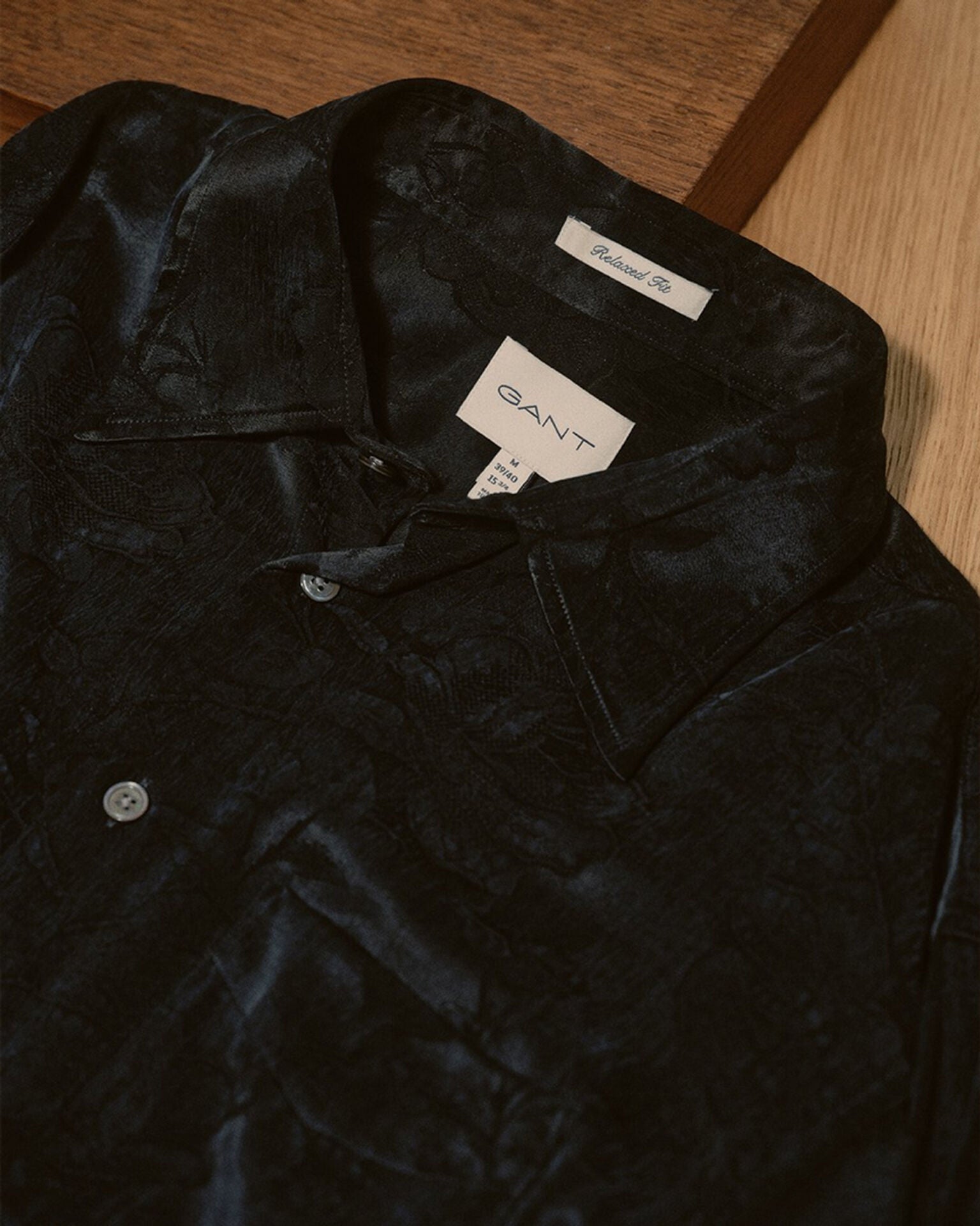 Black textured shirt with Gant label on a wooden surface